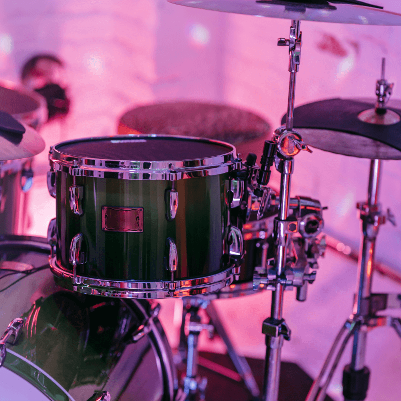 Drum set with a green snare drum in a blurred indoor setting