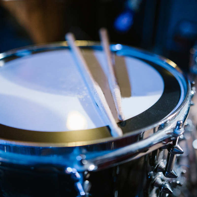 Close-up of a snare drum with drumsticks on a blurred background